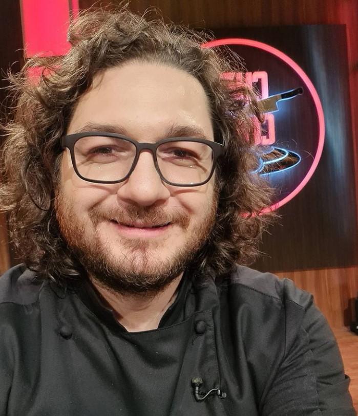 Chef Florin Dumitrescu, îmbrăcat în negru, zâmbind, la Chefi la cuțite
