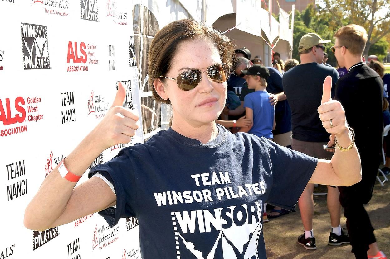 lara flynn boyle intr-un tricou si cu mainile ridicate