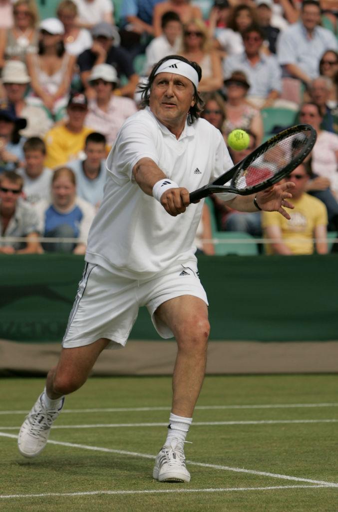 Ilie Năstase, jucând tenis, îmbrăcat în alb