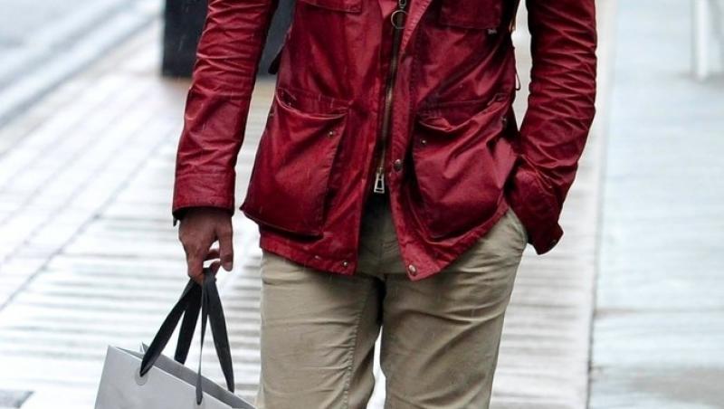 ryan thomas pe strada imbracat in crem, cu o jacheta rosie si basca gri