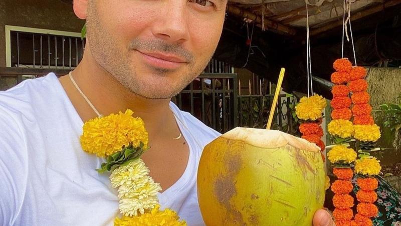 ryan thomas cu o nuca de cocos in mana, tricou alb si ghirlanda de flori