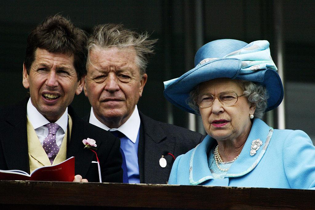 Regina Elisabeta, într-un costum albastru, alături de Sir Michael Oswald, într-un sacou negru