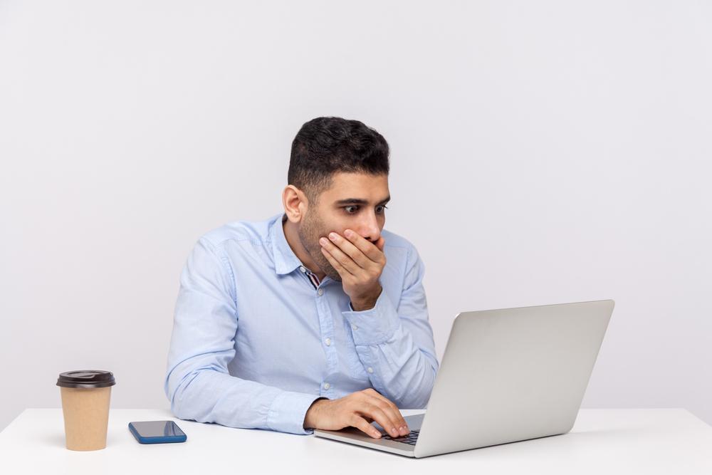 barbat cu mana la gura si privirea in laptop