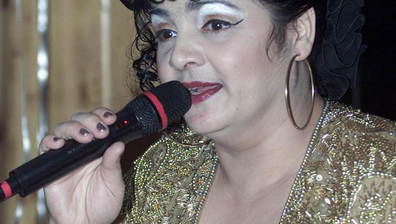 Cornelia Catanga, cântând la microfon, într-o ținută aurie