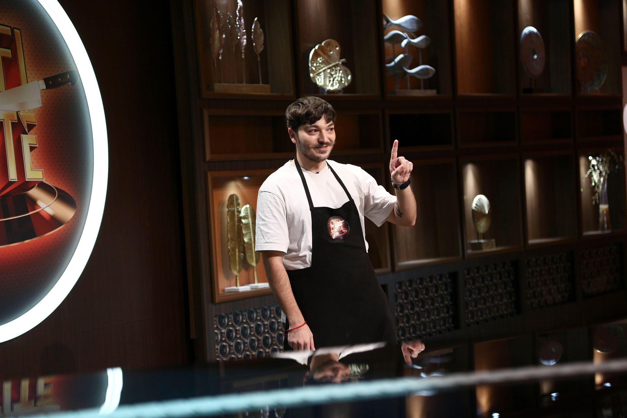 Theo Costache, cu șorțul Chefi la cuțite, este jurizat de către Chefi, ține mâna ridicată