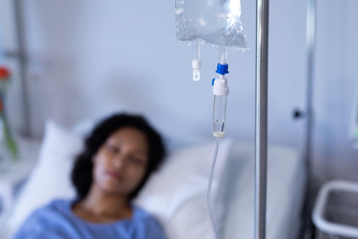 imagine cu o femeie pe patul de spital, stand la perfuzii