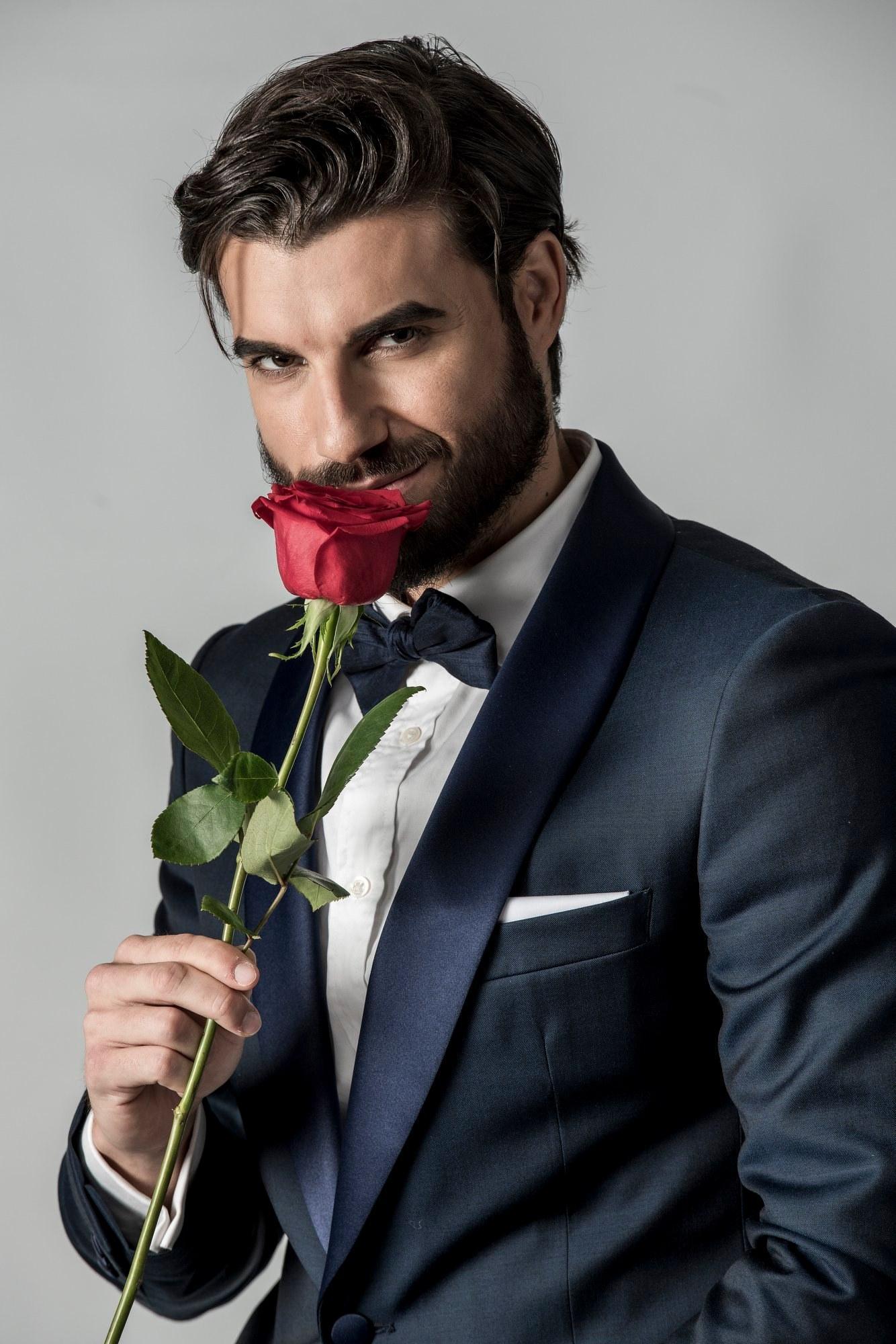 Andi Constantin, într-un costum albastru și un trandafir roșu în mână