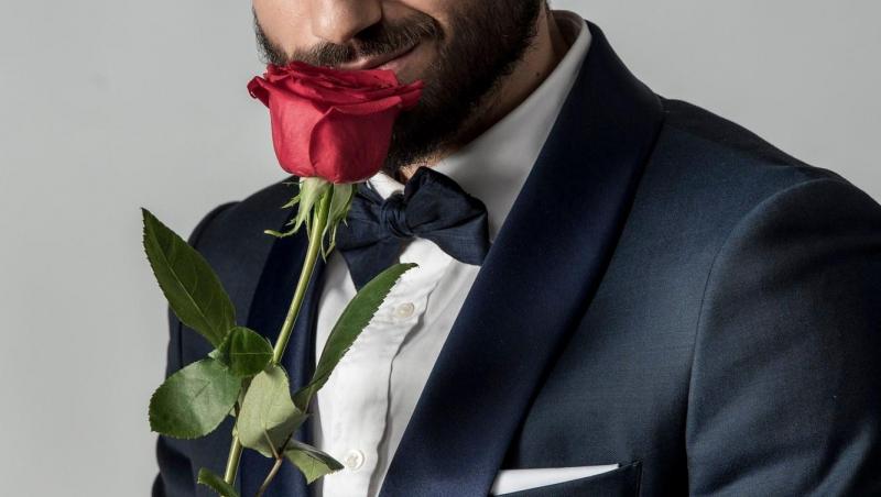 Andi Constantin, într-un costum albastru și un trandafir roșu în mână
