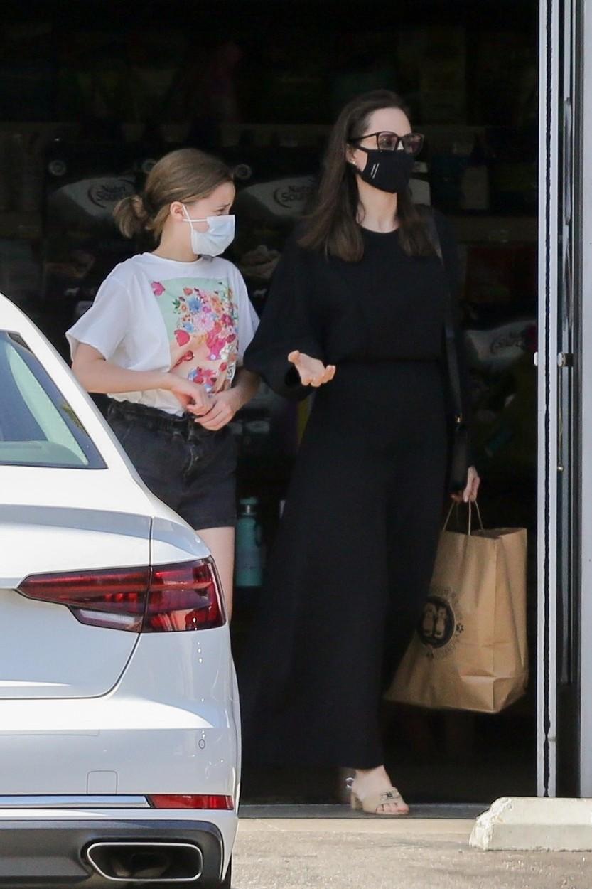 Angelina Jolie, îmbrăcată într-o rochie lungă, neagră, împreună cu una dintre fiice, pe stradă
