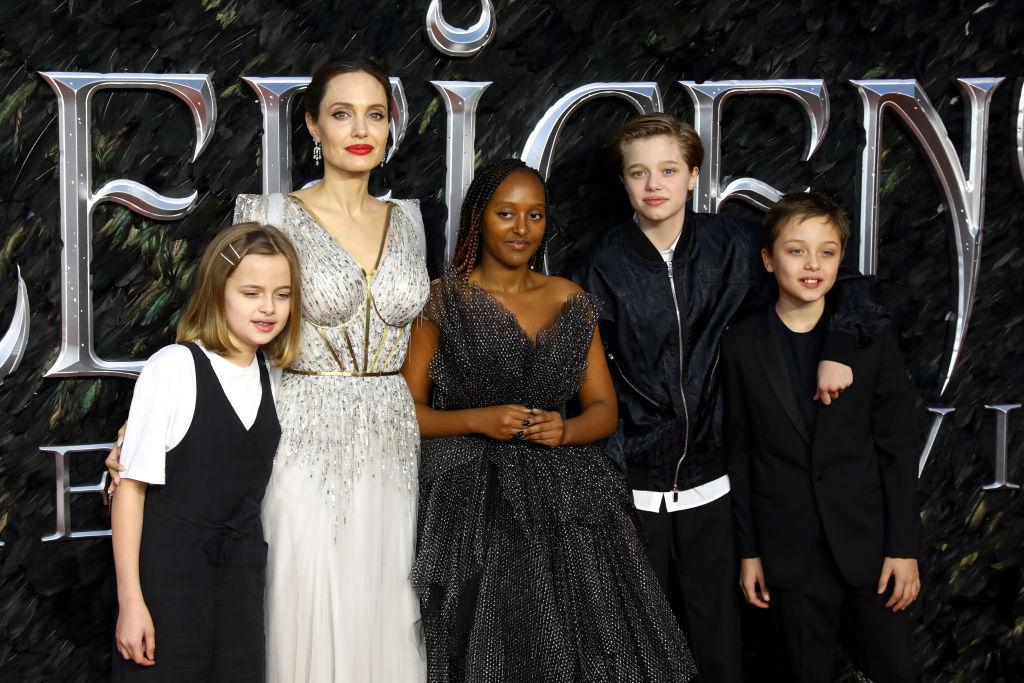 Angelina Jolie, îmbrăcată în rochie lungă, cu decolteu, împreună cu patru dintre copiii săi la evenimentul de lansare a filmului Maleficent