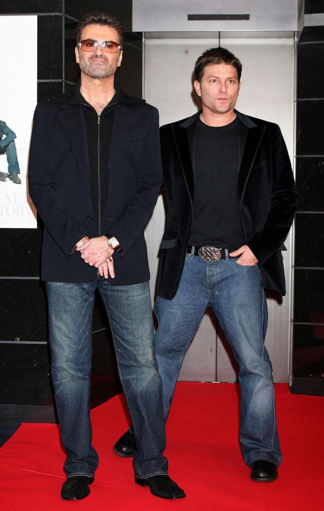 George Michael și fostul lui iubit, Kenny Goss, îmbrăcați amândoi cu sacouri negre și blugi deschiși la culoare