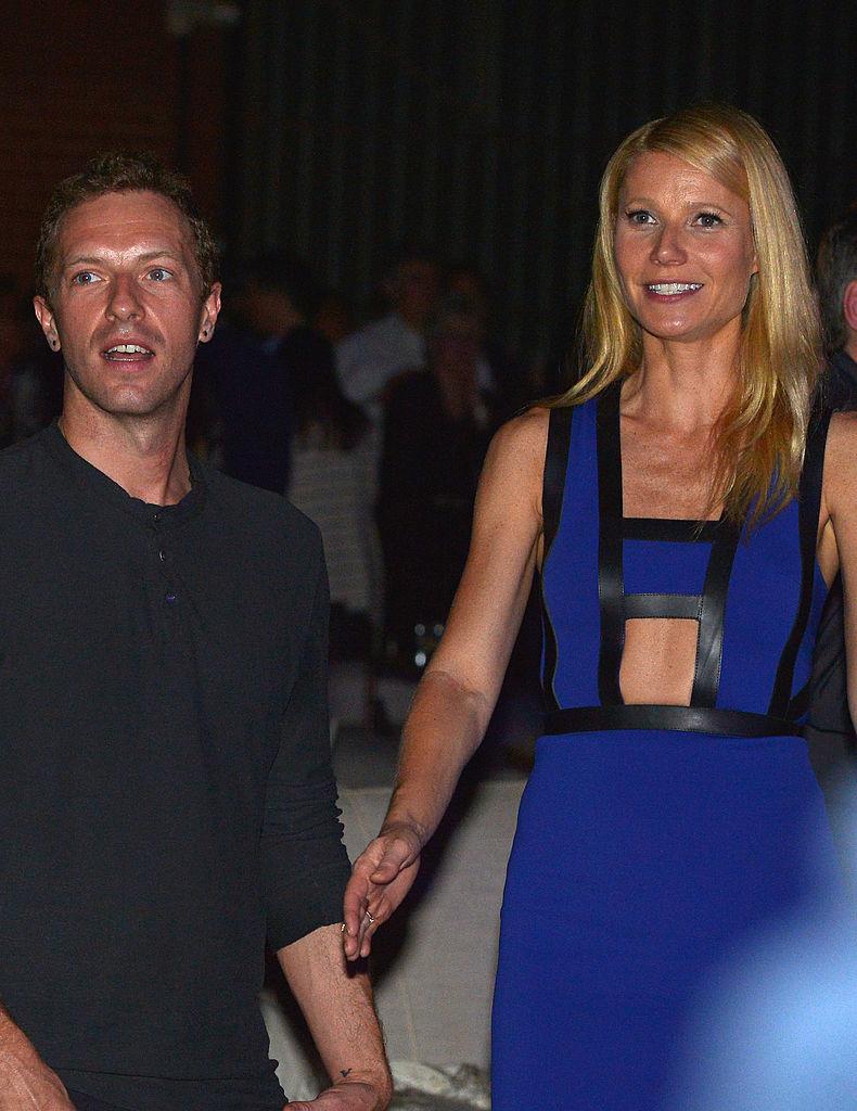 Gwyneth Paltrow și Chris Martin la un eveniment public. Ea este în rochie albastră, el, în cămașă neagră