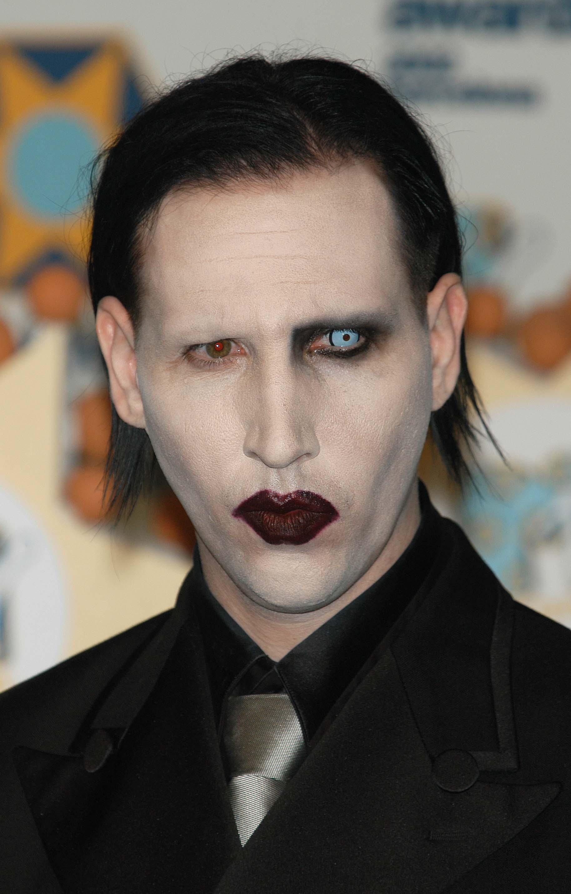 Marilyn Manson, îmbrăcat cu un costum negru, machiat strident, fotografiat la un eveniment muzical
