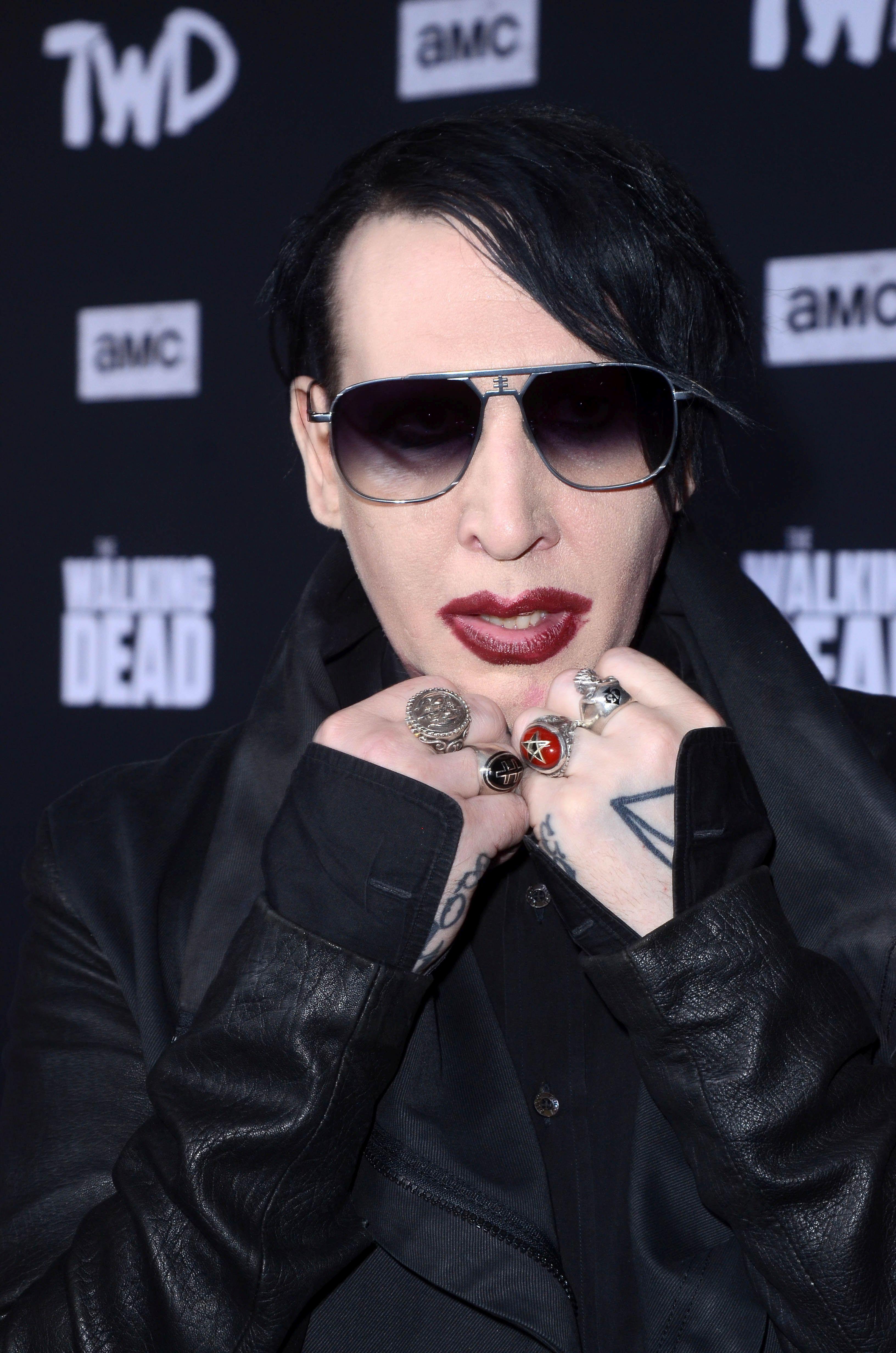 Marilyn Manson, îmbrăcat în negru, cu ochelari de soare, machiat