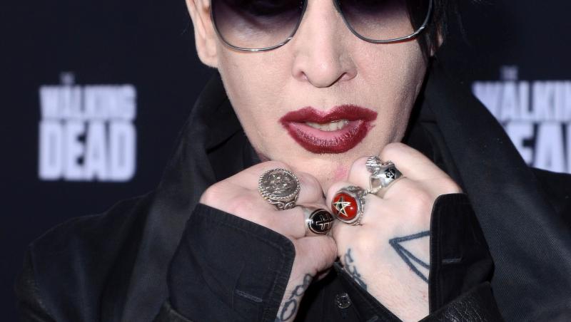 Marilyn Manson fotografiat la un eveniment monden, îmbărcat în negru, cu ochelari de soare pe ochi.