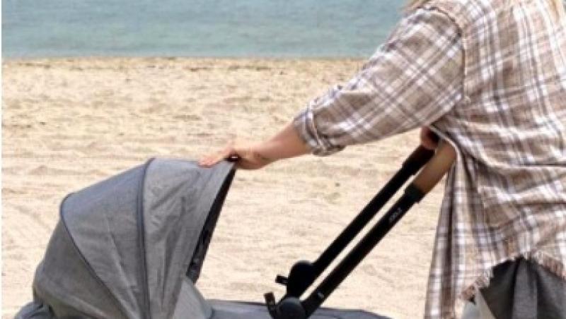Gina Pistol, împingând căruțul cu micuța Josephine, la malul mării
