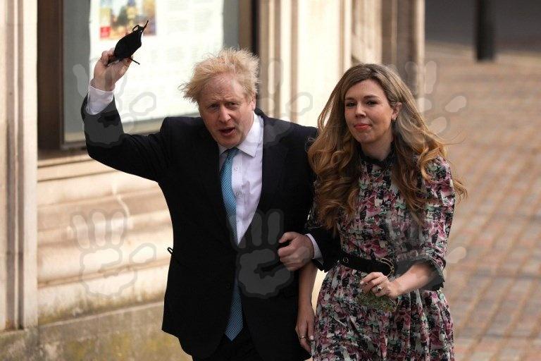 Boris Johnson, purtând sacou și cămașă și Carrie Symonds, într-o rochie înflorată
