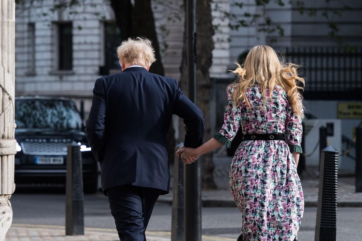 Boris Johnson îmbrăcat la costum și Carrie Symonds  în rochie înflorată, cu spatele