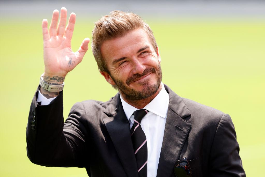 David Beckham într-un costum negru și cămașă albă, cravață neagră