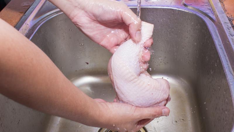 imagine cu mainile unei persoane care spala o bucata de pui