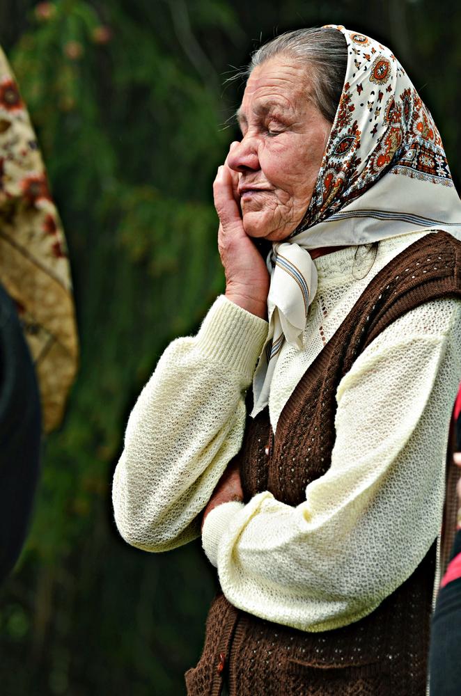 femeie în vârstă care isi tine mana la obraz