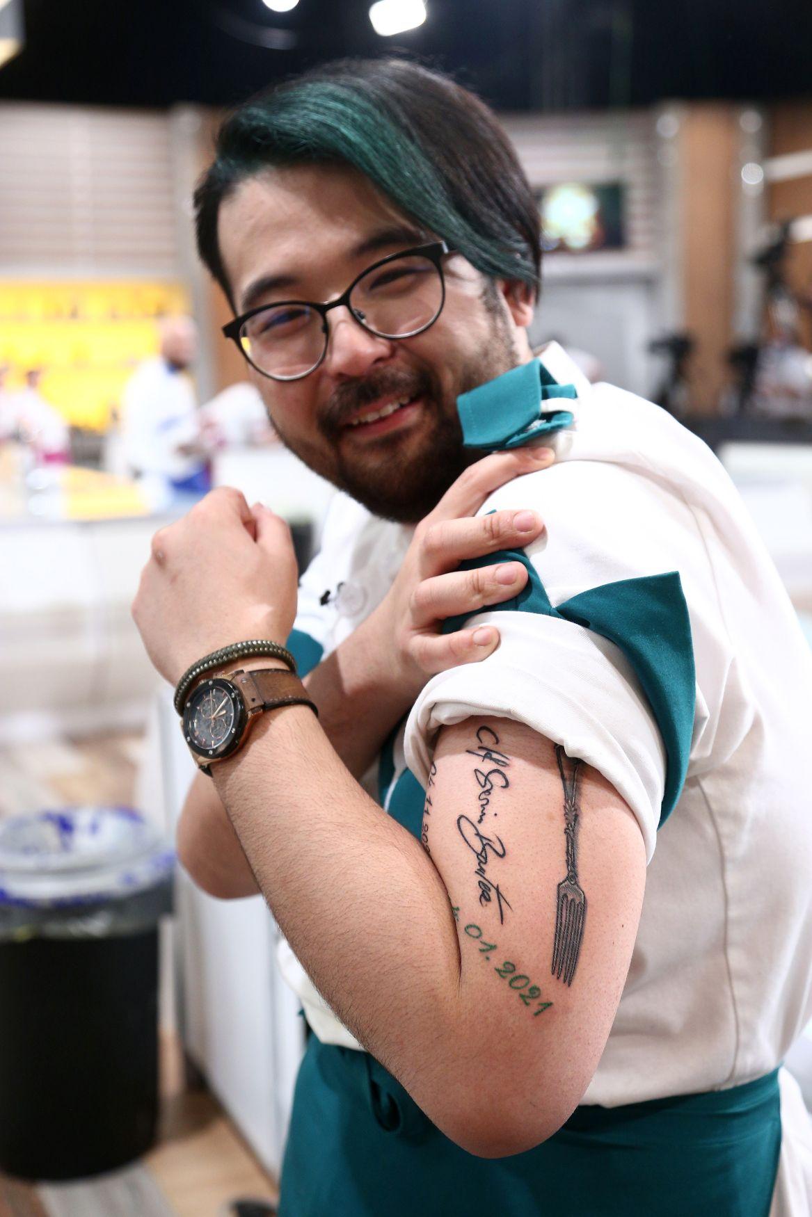 Rikito Watanabe în tunica albă - verde, își arată tatuajul
