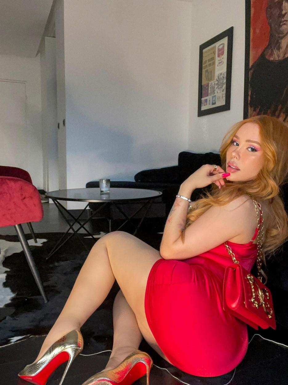 Maria Viera, îmbrăcată într-o rochie sexy, roșie, stă întoarsă într-o parte către fotograf