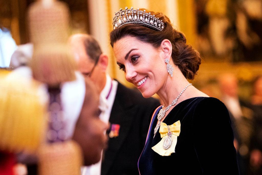 Kate Middleton, îmbrăcată într-o rochie neagră, în cadrul unui eveniment oficial la Palatul Buckingham, în 2019, purtând, de asemenea, Ordinul Familiei Regale, primit de la Regină