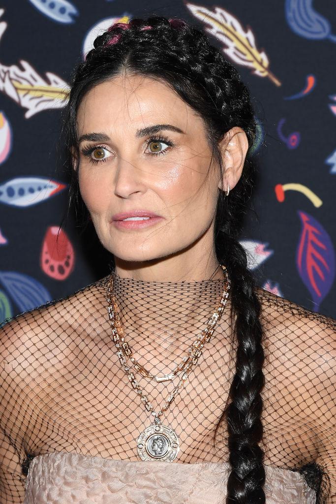 Demi Moore, cu părul prins într-o coadă împletită, și îmbrăcată într-o rochie crem, cu plasă în partea de sus, și cu lanțuri la gât