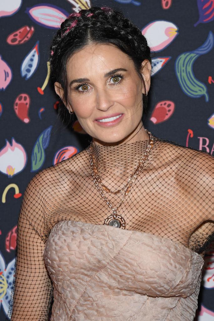 Demi Moore, cu părul prins într-o coadă împletită, și îmbrăcată într-o rochie crem, cu plasă în partea de sus, și cu lanțuri la gât