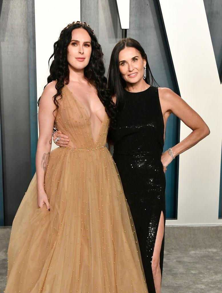 Demi Moore și una dintre fiicele ei, Rumer Willis, în februarie 2020. Rumer este îmbrăcată într-o rochie lungă, aurie, iar mama ei, Demi Moore, este îmbrăcată într-o rochie neagră