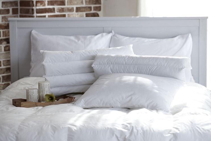 Un pat cu lenjerie albă și perne albe