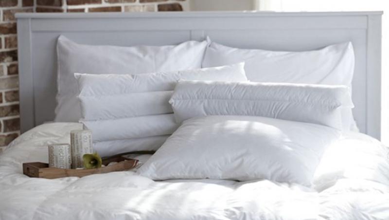Un pat cu lenjerie albă și perne albe