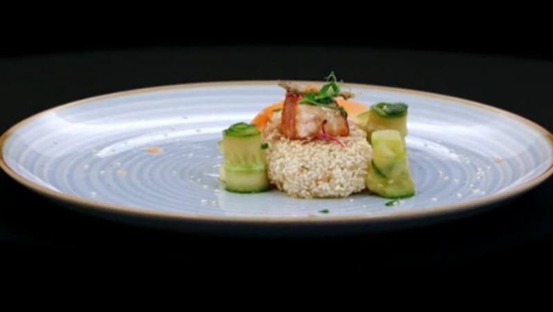 Somon Teriyaki pe pat de orez cu susan, alături de salată de castraveți pe o farfurie albă