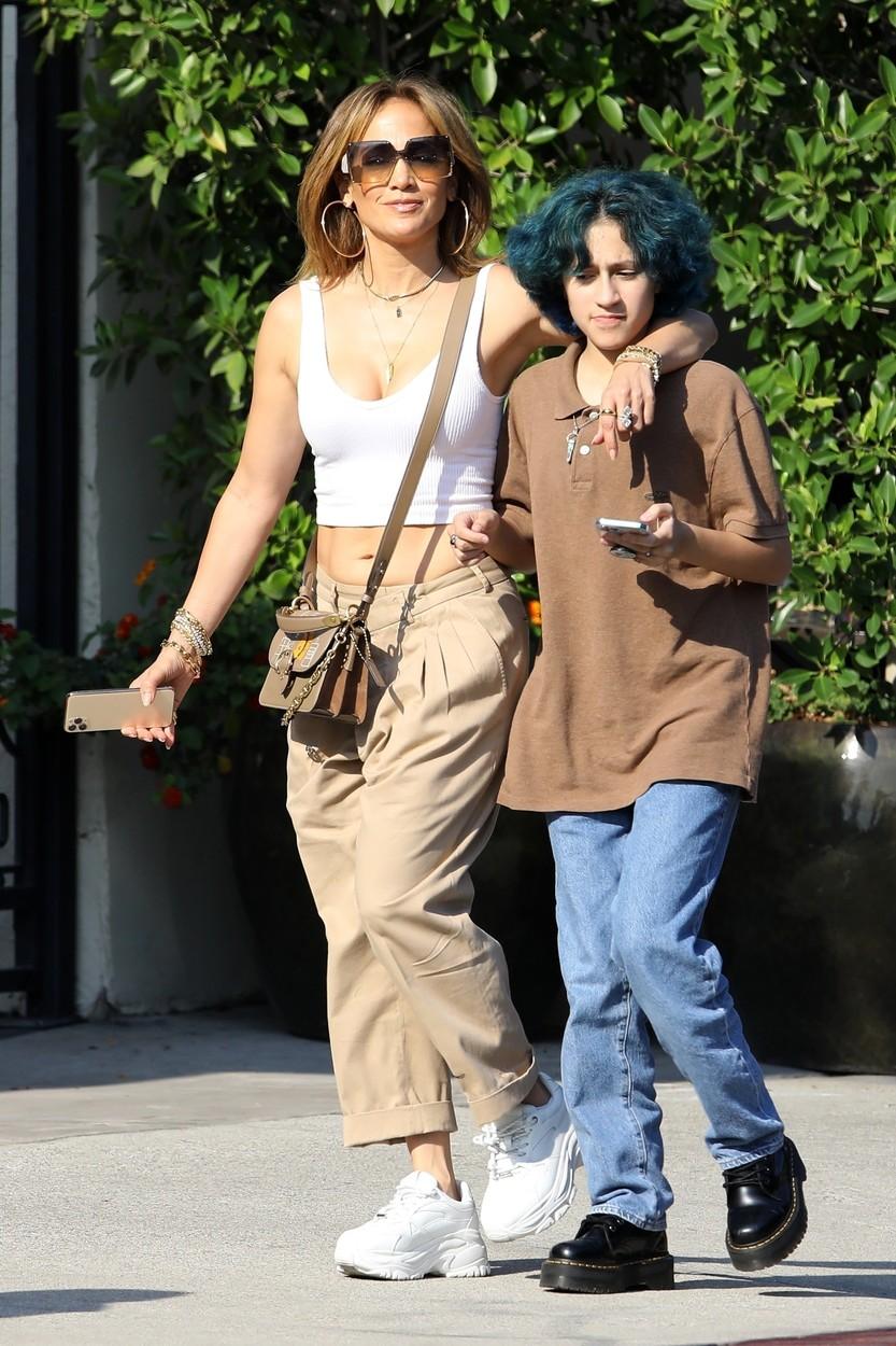 jennifer lopez si fiica ei emme pe strada, tinandu-se de mana, jlo poarta un top alb, geanta bej, pantaloni bej, tenesi albi, iar emme blugi albastri, parul albastru si un tricou maro