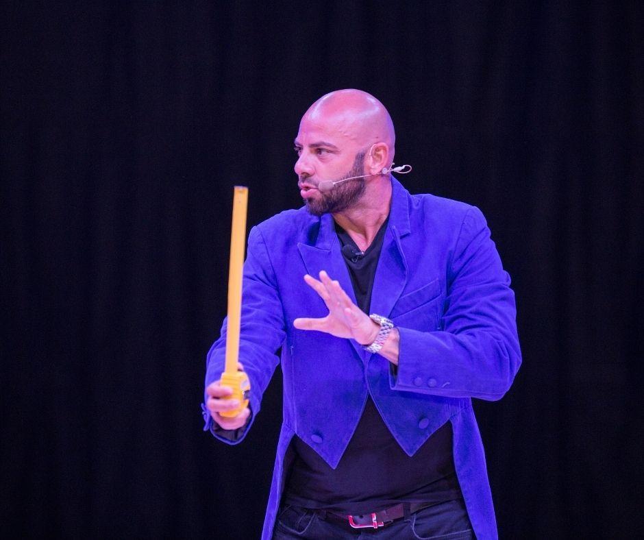 Giani Kiriță în sacou albastru de magician, ține o riglă în mână