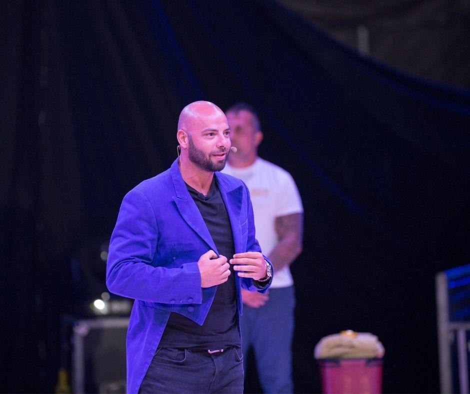 Giani Kiriță în sacou albastru de magician, tricou negru și jeans albaștri