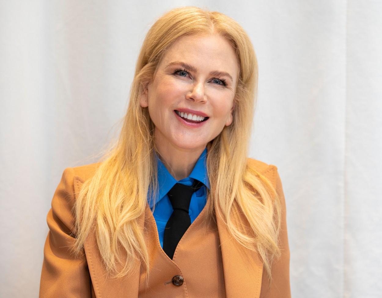 nicole kidman intr-un costum portocaliu, cu cravata neagra si camasa albastra