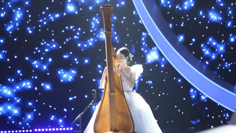 maria ene pe scena la next star intr-o rochie alba cantand la harpa