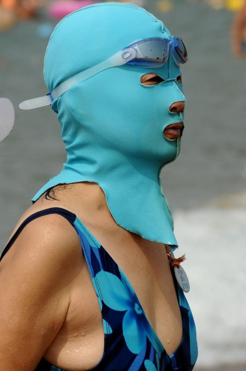 Femeie purtând o mască Facekini bleu, îmbrăcată în costum de baie