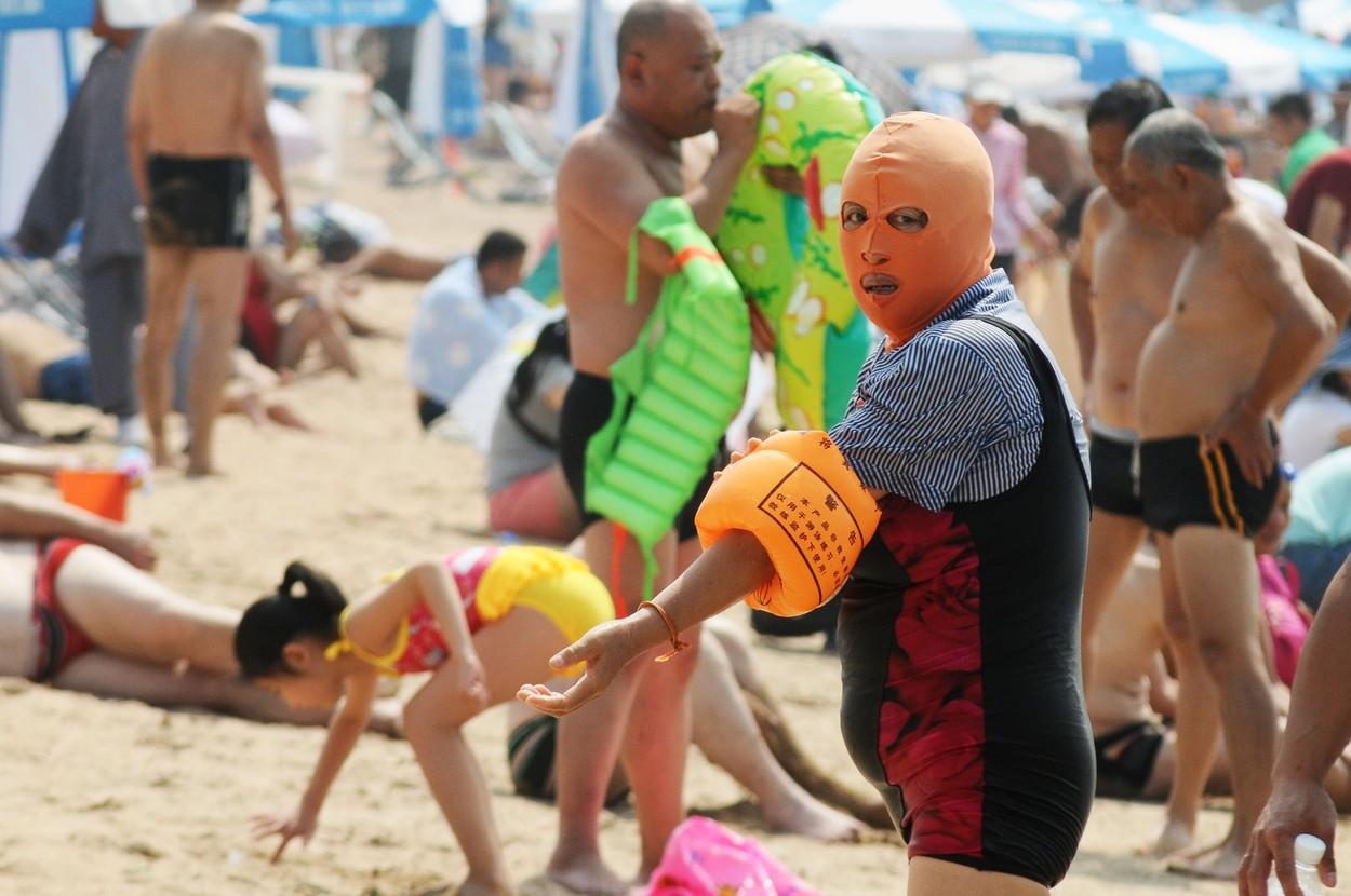O persoană, pe plajă, purtând masca "Facekini"