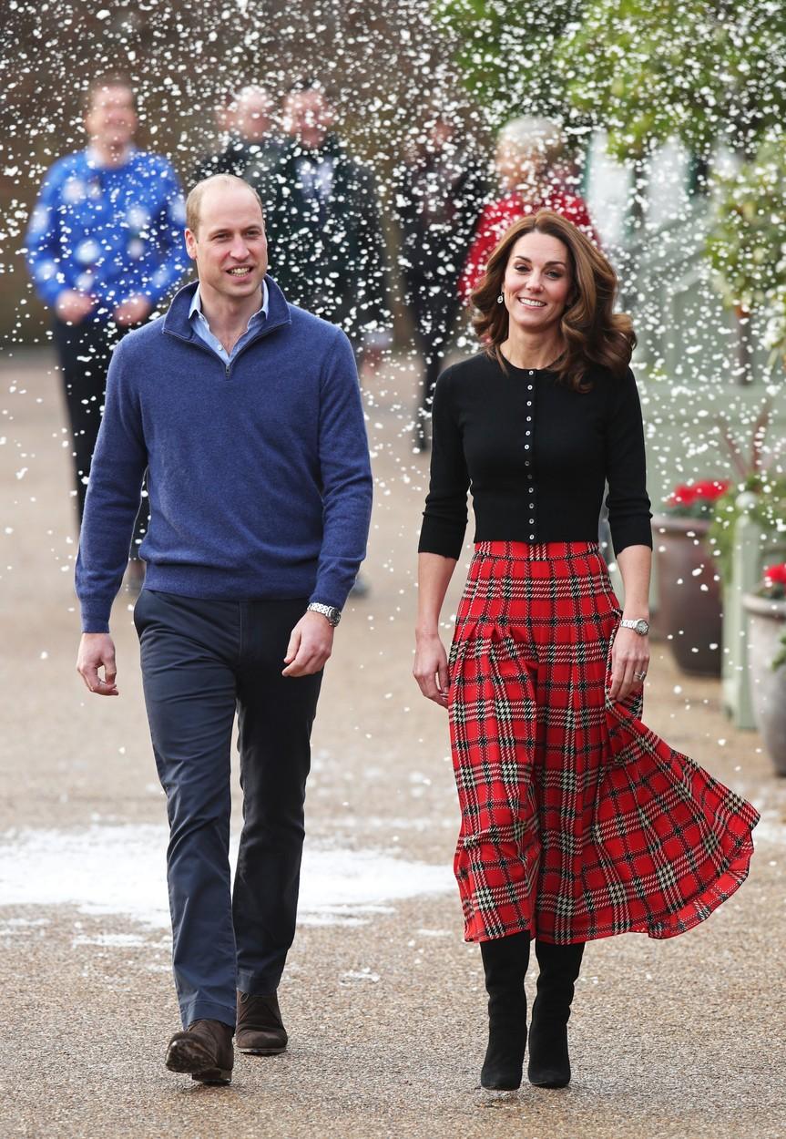 kate middleton intr-o bluza neagra, fusta rosie in carouri si printul william intr-un pulover albastru si pantaloni bleumarin