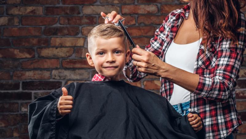 Poză generală cu un băiat care este tuns de un frizer
