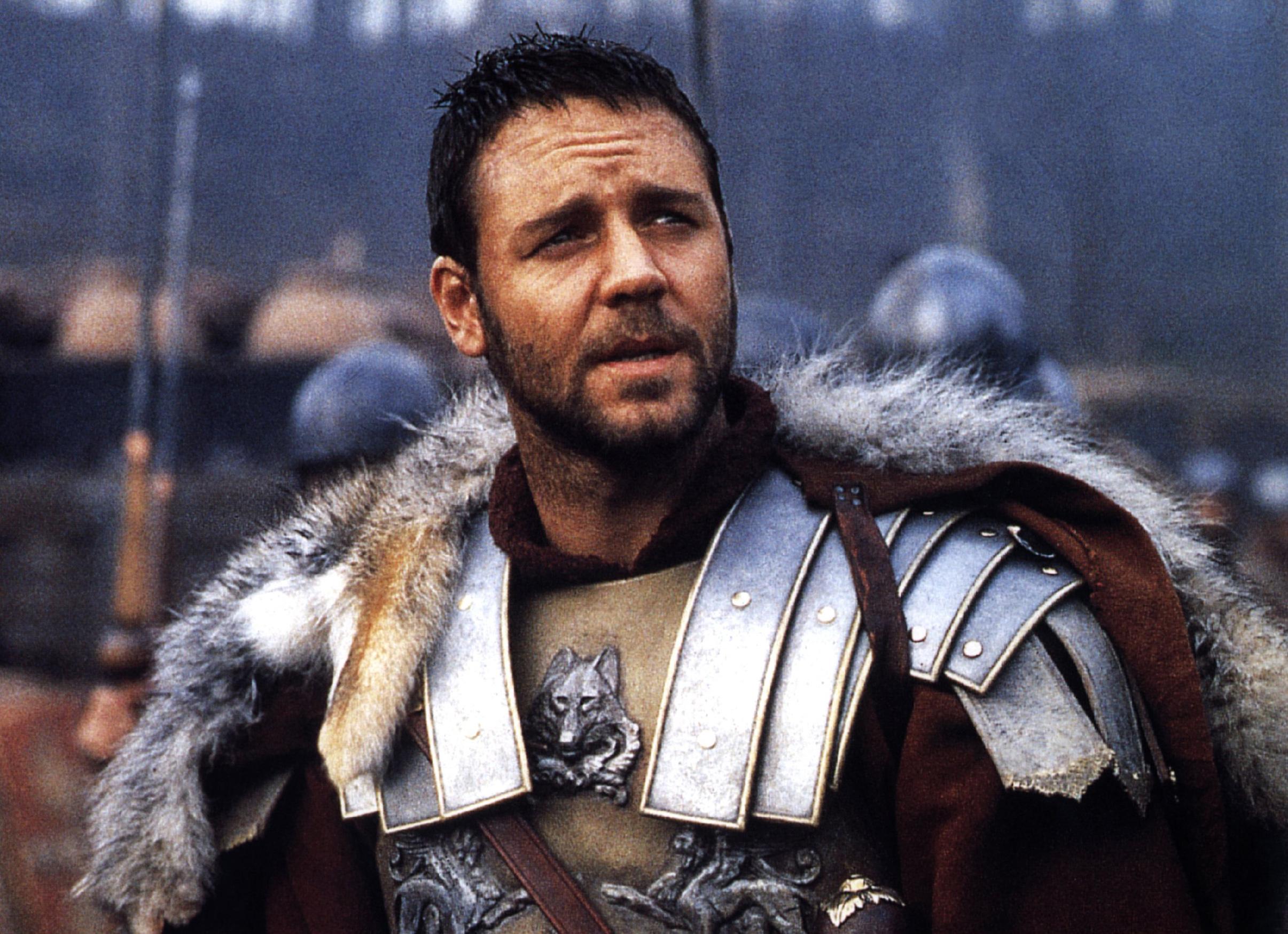 russell crowe în filmul gladiatorul, pe terenul de luptă, îmbrăcat în armura de general roman, cu armură arginie și pelerină roșie cu blană