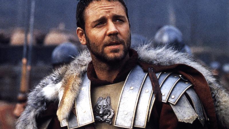 russell crowe în filmul gladiatorul, pe terenul de luptă, îmbrăcat în armura de general roman, cu armură arginie și pelerină roșie cu blană