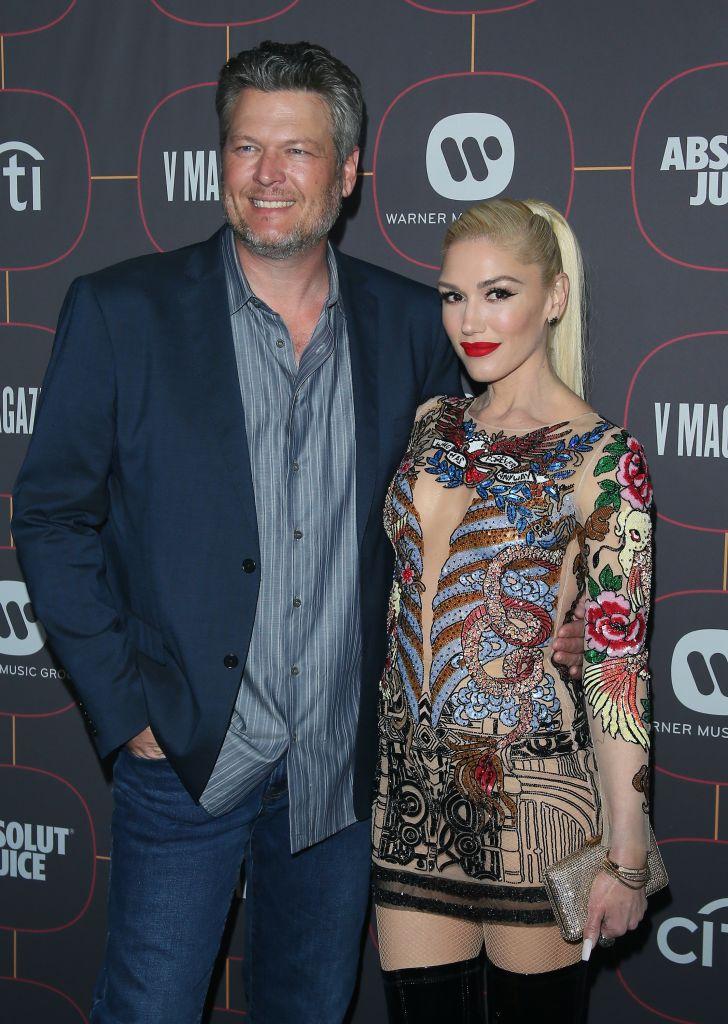 Gwen Stefani si sotul ei, Blake Shelton, la un eveniment public. El, în sacou și cămașă, ea, într-o rochie colorată, cu buze roșii