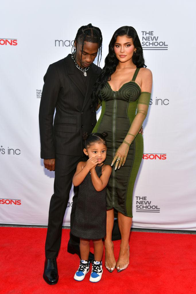 Kylie Jenner, îmbrăcată elegant, într-o rochie, cu părul desprins, împreună cu Travis Scott și Stormi, fetița lor