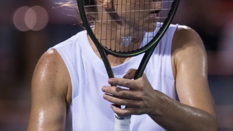 Simona Halep, ținându-și paleta de tenis în dreptul feței