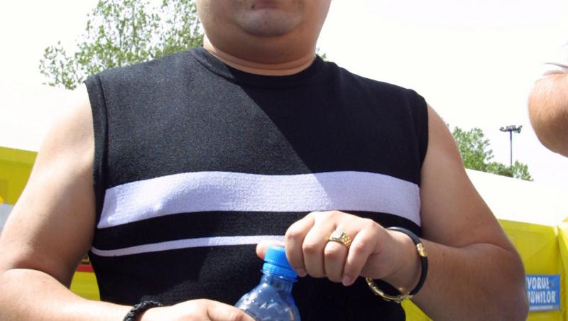 Adrian Minune într-un tricou alb, ține sticla de apă în mână