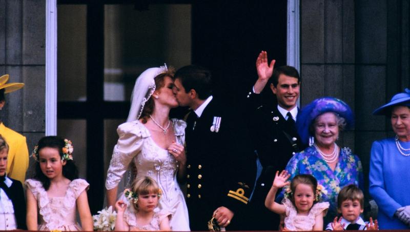 sarah ferguson și prințul andrew, ziua căsătoriei, sărut pe balcon. ea îmbrăcată în ochia de mireasă, el în uniforma neagră, cu familia regală pe lângă ei